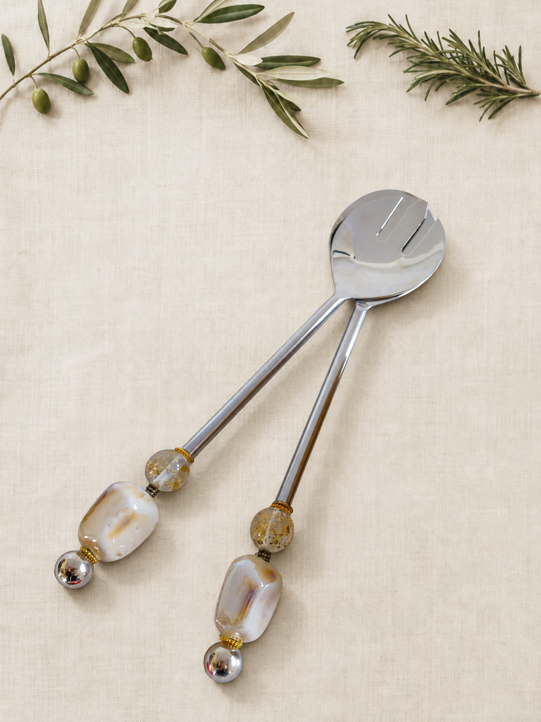 The Alya salad serving set with silver-coloured utensils, ivory pearlescent beads, clear gold-flecked accents and polished silver end beads.