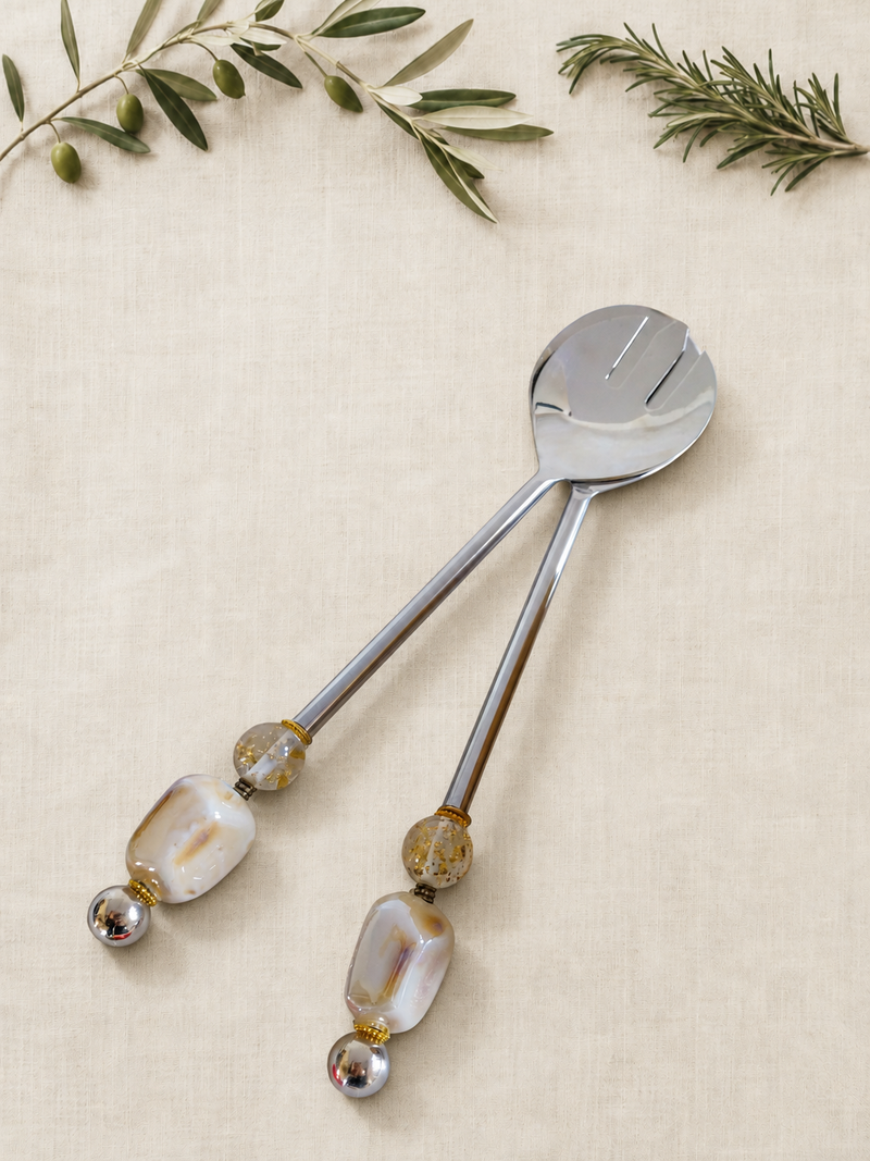 The Alya salad serving set with silver-coloured utensils, ivory pearlescent beads, clear gold-flecked accents and polished silver end beads.