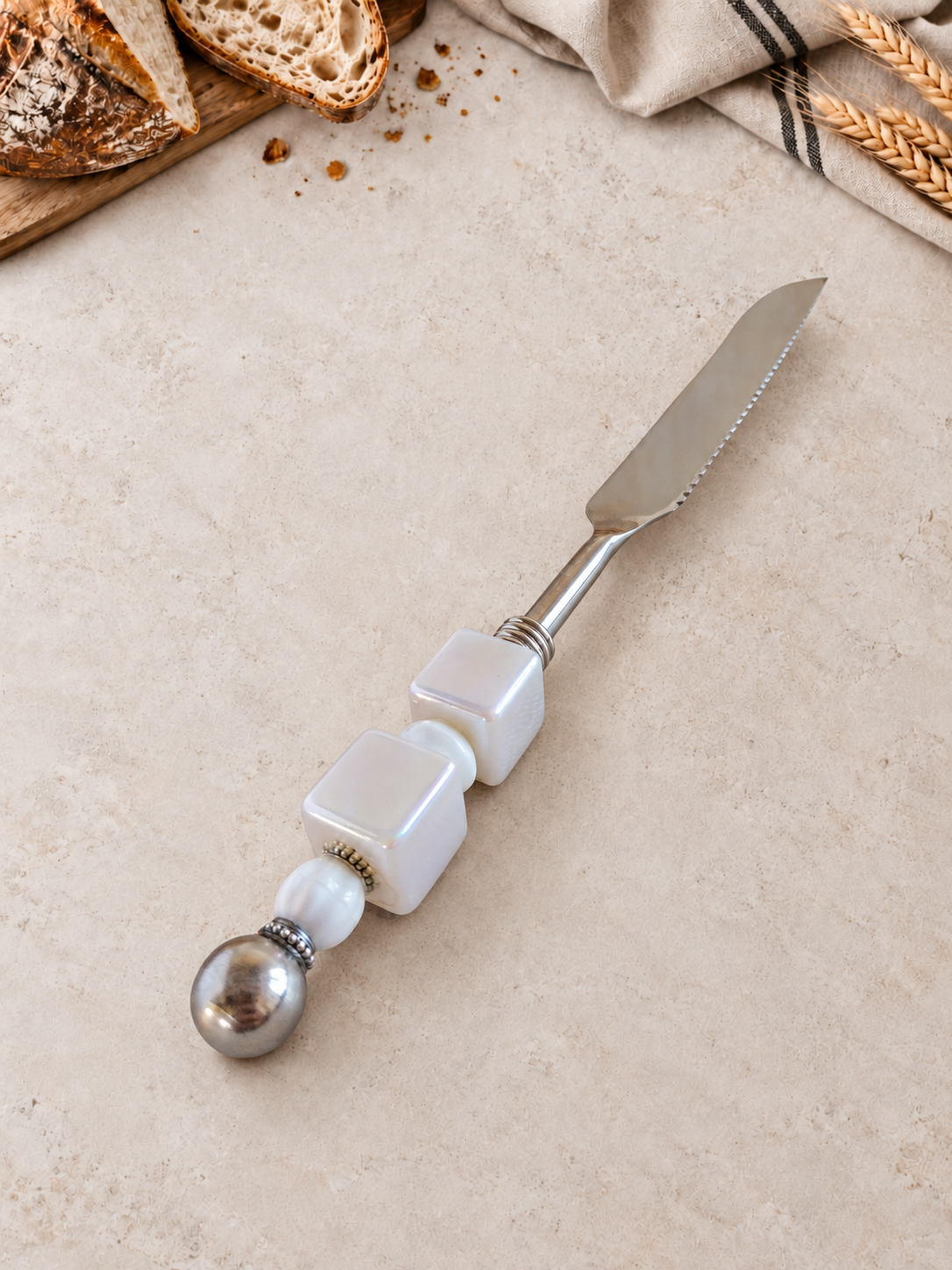 The Badir bread knife with a stainless steel blade and a decorative white pearl-look beaded handle.