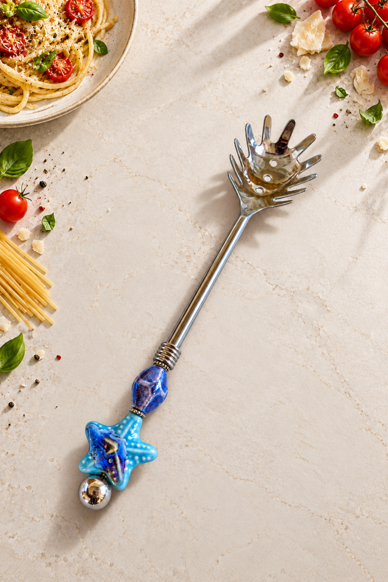 The Chanda decorative pasta spoon with a silver-coloured spaghetti server head, blue marbled beads, a starfish detail and handcrafted silver accents.