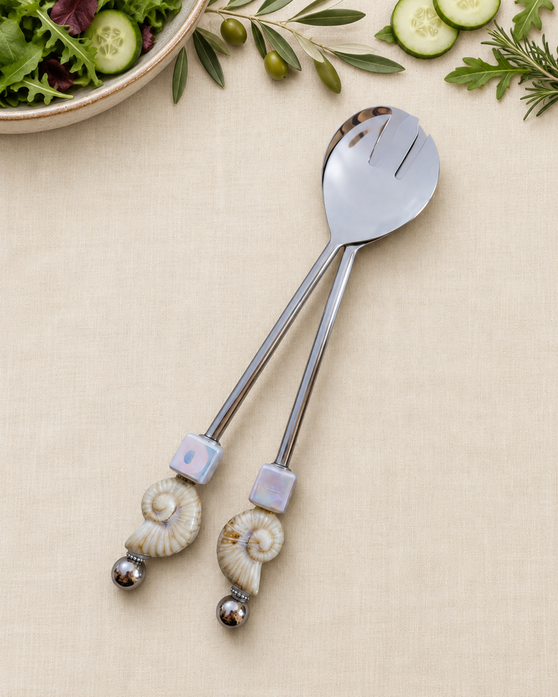 Alt-tekst: The Devina salad serving set featuring a silver-coloured spoon and slotted server with square pearlescent beads, ivory spiral shell details and polished silver end beads.