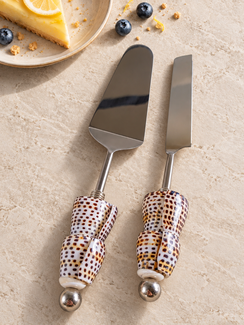 The Dunya decorative cake serving set with a silver-coloured cake knife and cake server, patterned shell handles in cream, brown and black, and polished silver end beads.