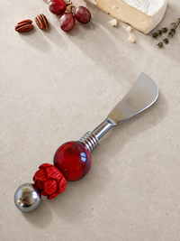 The Felita decorative butter knife with a silver blade, a large red glass bead, a smaller faceted red bead and a silver end bead.