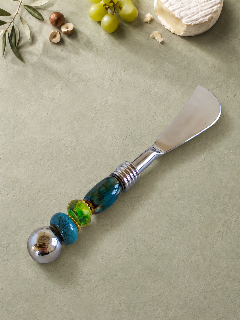 The Kalan decorative butter knife with a silver blade, blue and green glass beads, gold-coloured accents and a polished silver end bead.