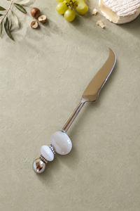 The Masoom decorative cheese knife with a silver-coloured curved blade, a large pearlescent white bead, a smaller white accent bead and a polished silver end bead.