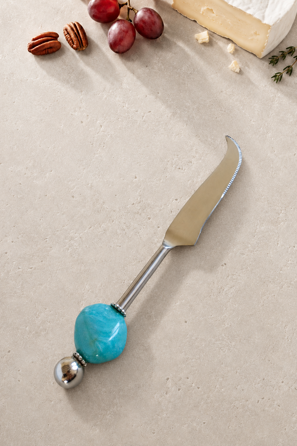 The Emrah cheese knife featuring a silver-coloured curved blade, a translucent pale yellow bead, a bright yellow disc bead and a polished silver end bead.