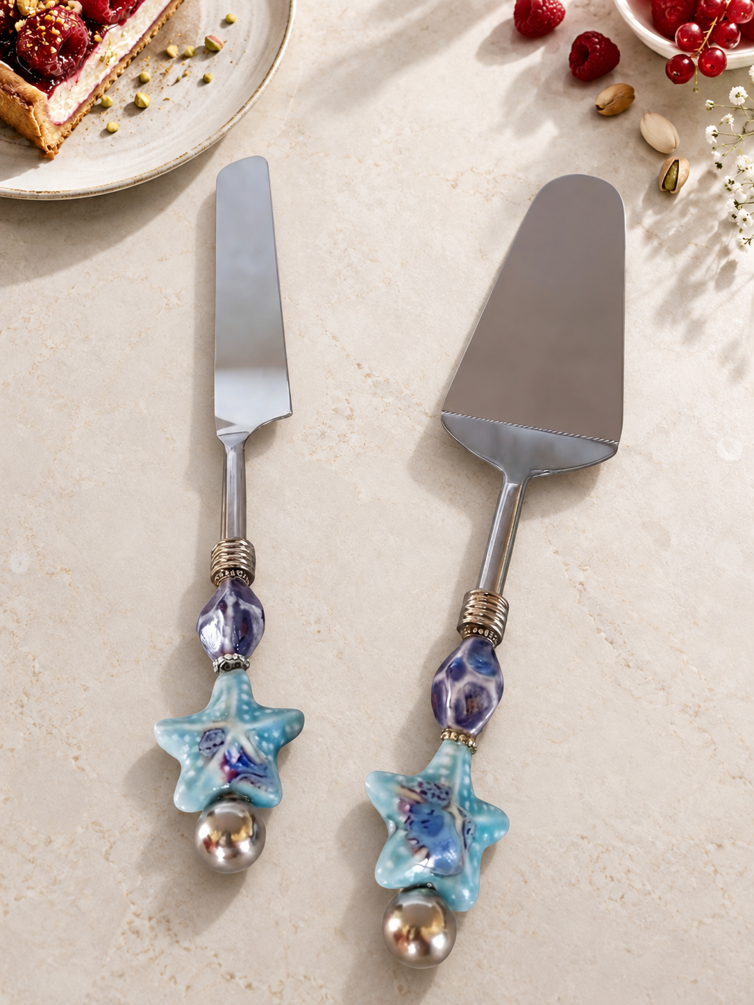 The Romil cake serving set featuring a silver-coloured cake knife and cake server with blue and purple glass beads, turquoise starfish details and polished silver end beads.
