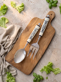 The Avani salad serving spoon and fork with silver heads and white and black resin handles