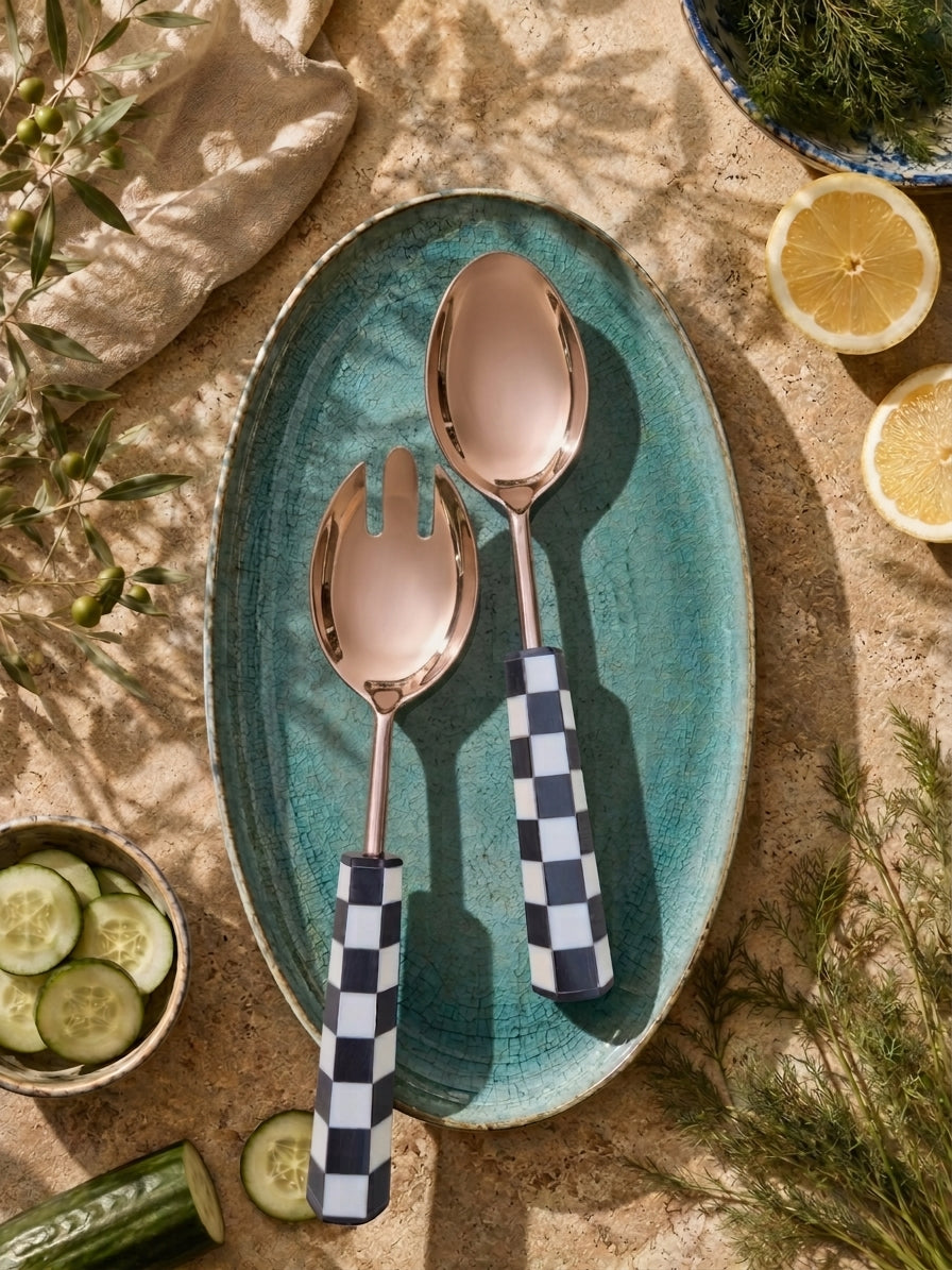 The Azara salad serving set with rose gold finish and black and white checkered handles