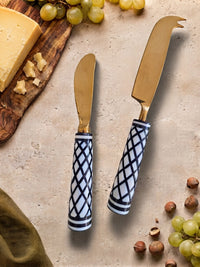 Two cheese knives with gold heads and black and white resin handles, The Elara
