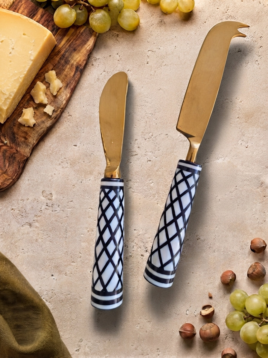 Two cheese knives with gold heads and black and white resin handles, The Elara