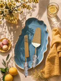 The Embun cake knife and server with gold blades and clear beaded handles
