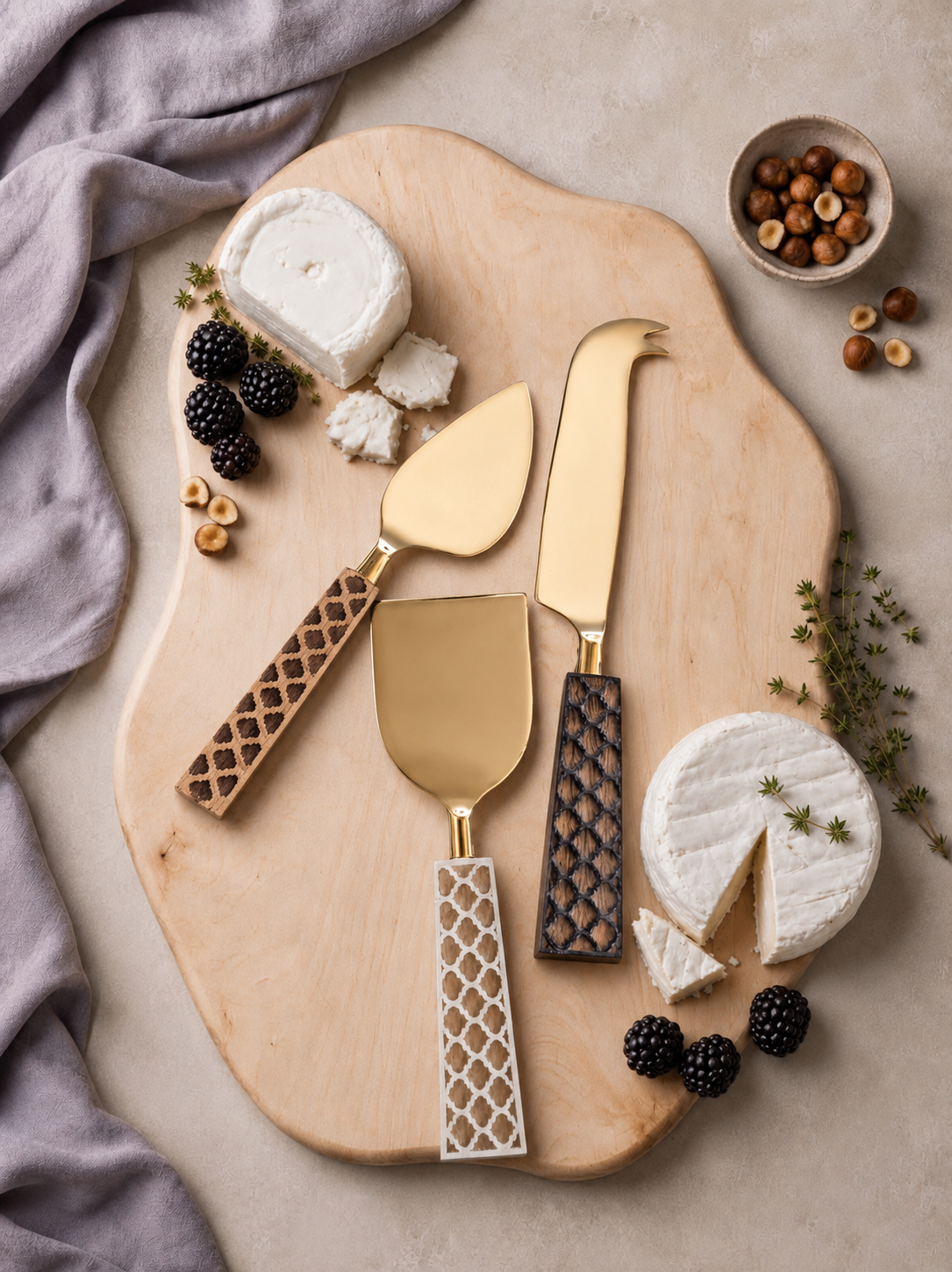 Three cheese knives with gold heads and brown, ivory and dark brown decorative handles, The Kartika