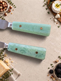 Close up of The Maraya cheese knives with silver heads and jade green resin handles