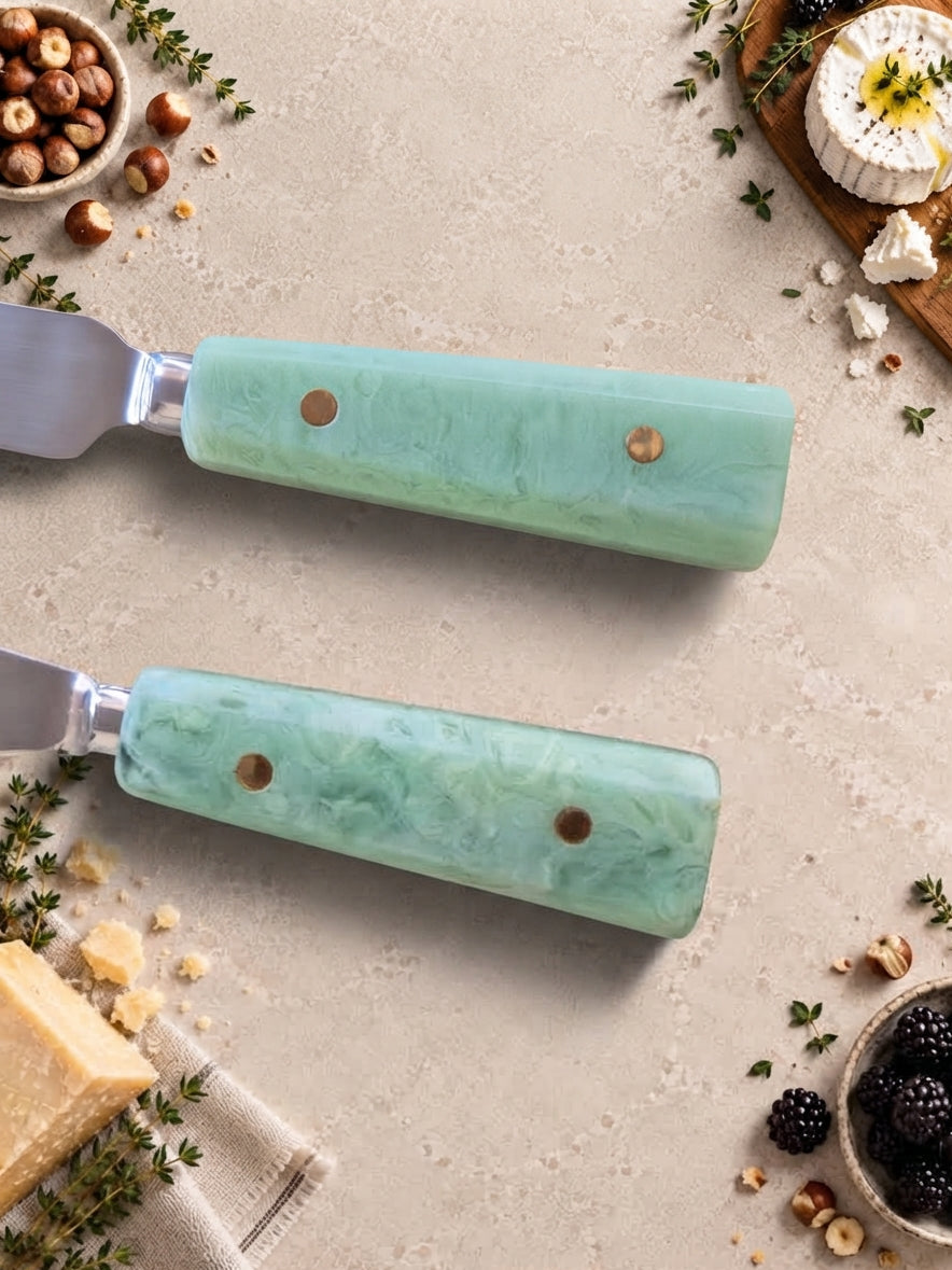 Close up of The Maraya cheese knives with silver heads and jade green resin handles