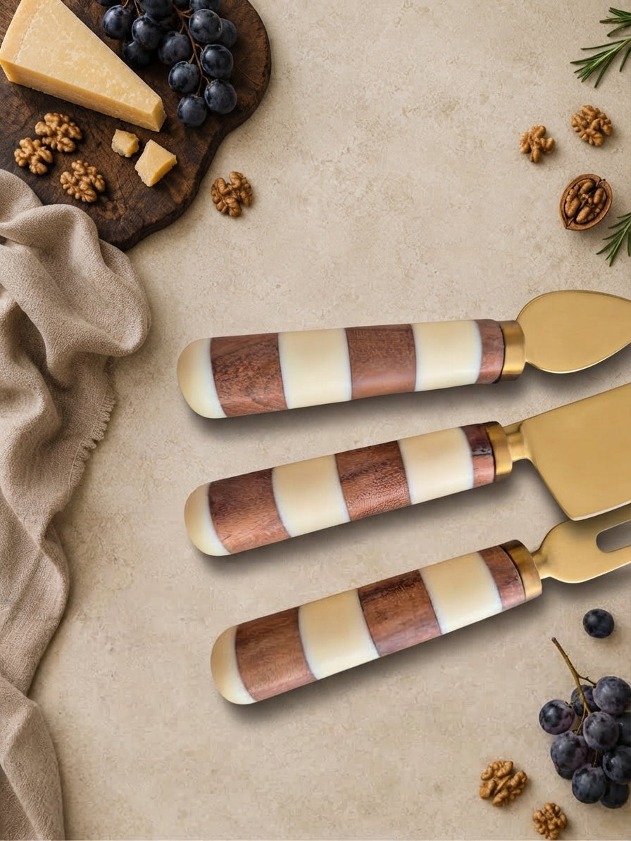 Close up of The Nalaya cheese knives with gold heads and brown and ivory striped handles