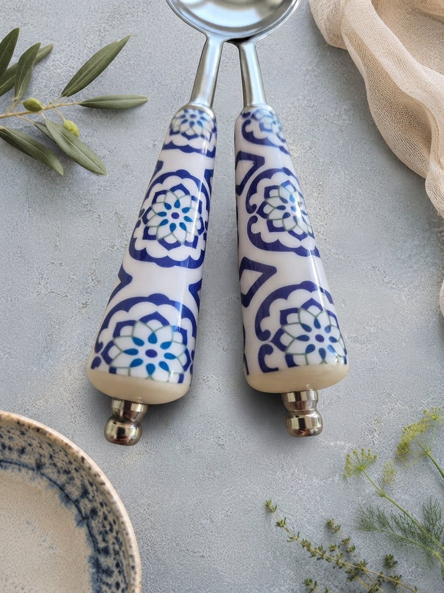 Close up of The Ravina salad servers with silver heads and blue and white decorative handles