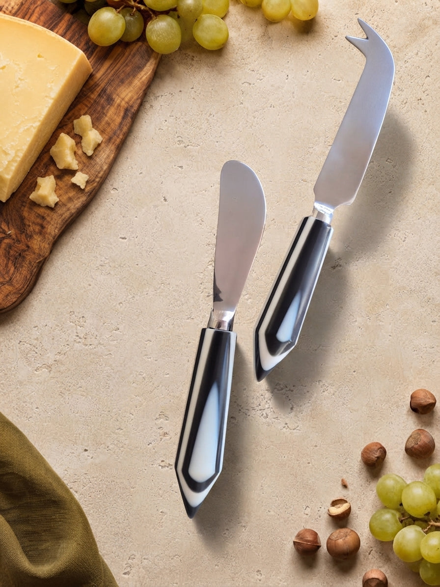 Two cheese knives with silver heads and glossy black and white handles, The Rona