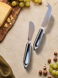 Two cheese knives with silver heads and glossy black and white handles, The Rona