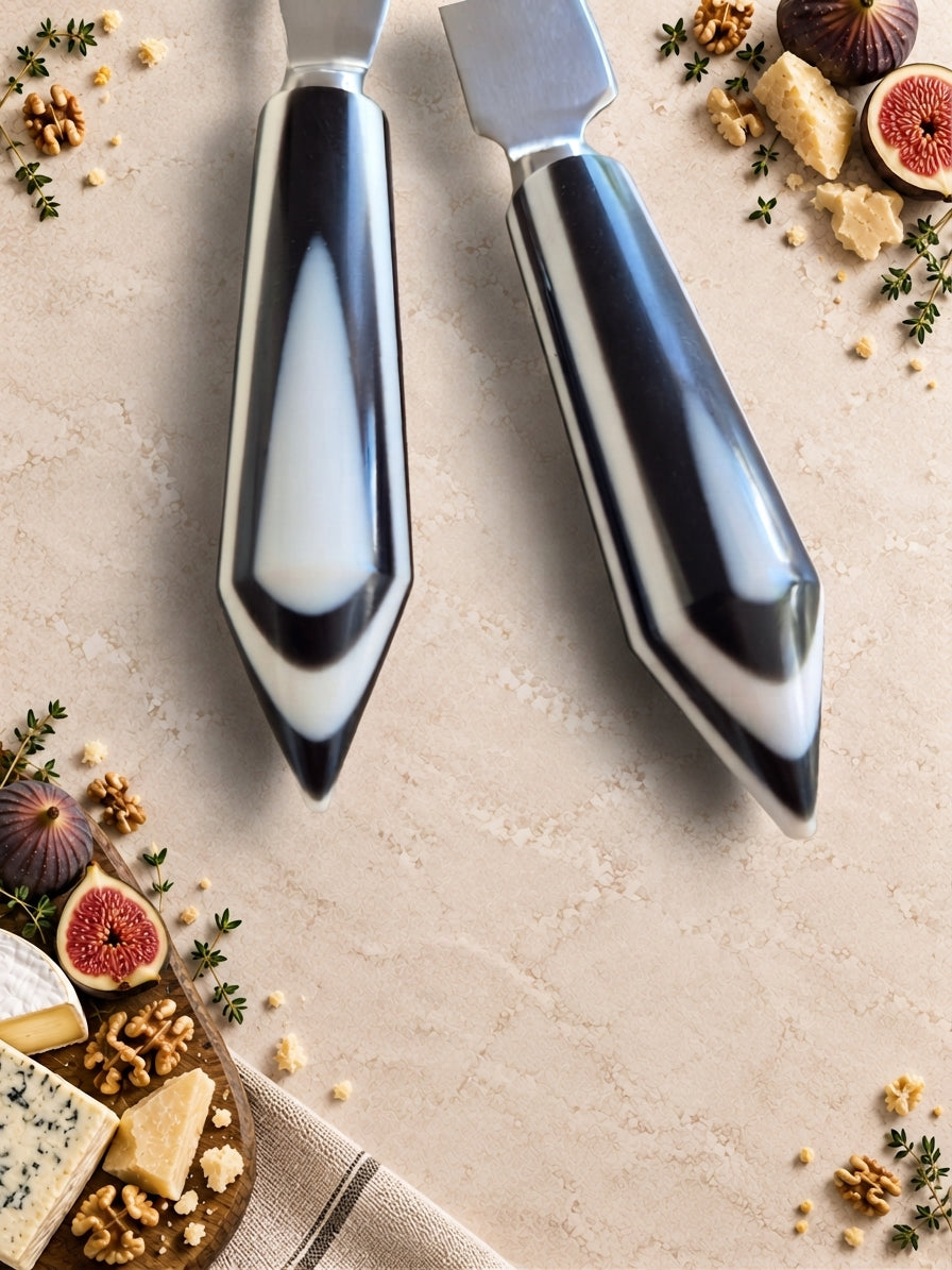 Close up of The Rona cheese knives with silver heads and black and white handles