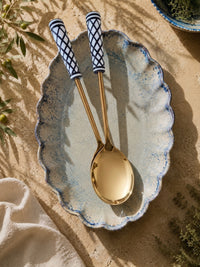 The Savira serving spoon and fork with gold stems and black and white patterned handles
