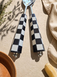 Detail of the black and white checkerboard resin handles with silver stems on The Talisa salad serving set