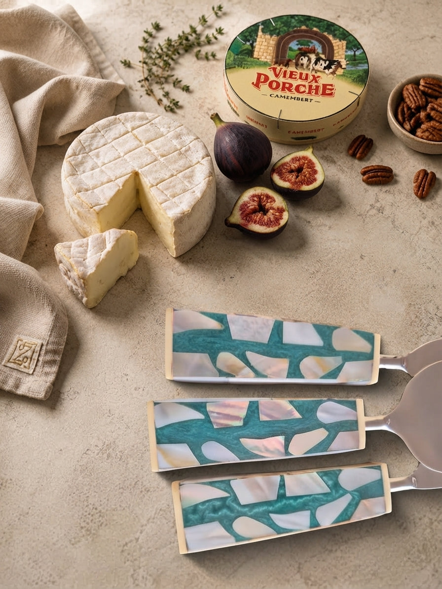 Close up of The Teratai cheese knives with silver heads and turquoise, white and beige mosaic handles